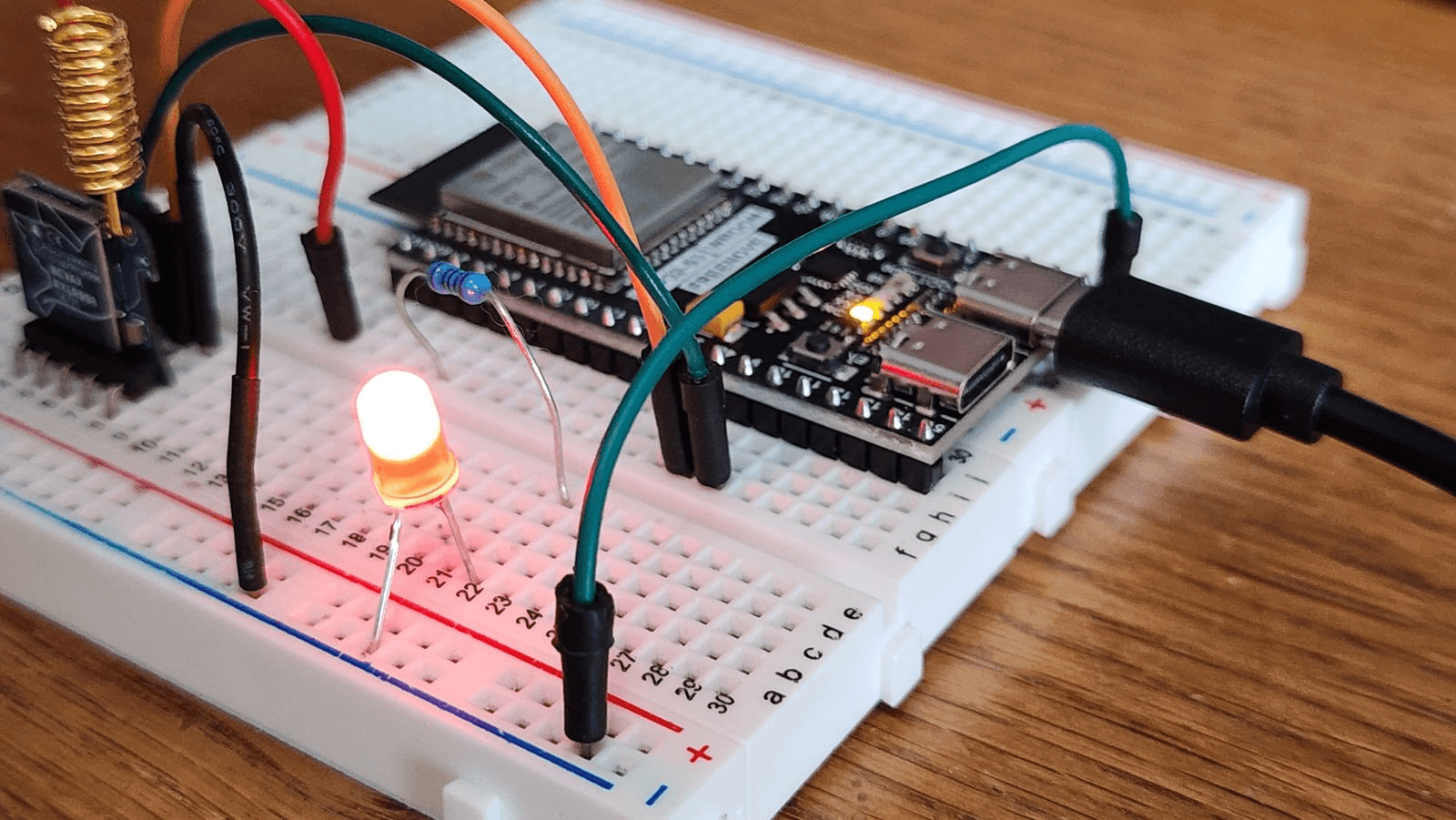 Glowing LED and resistor on a breadboard wired to an ESP32 development board