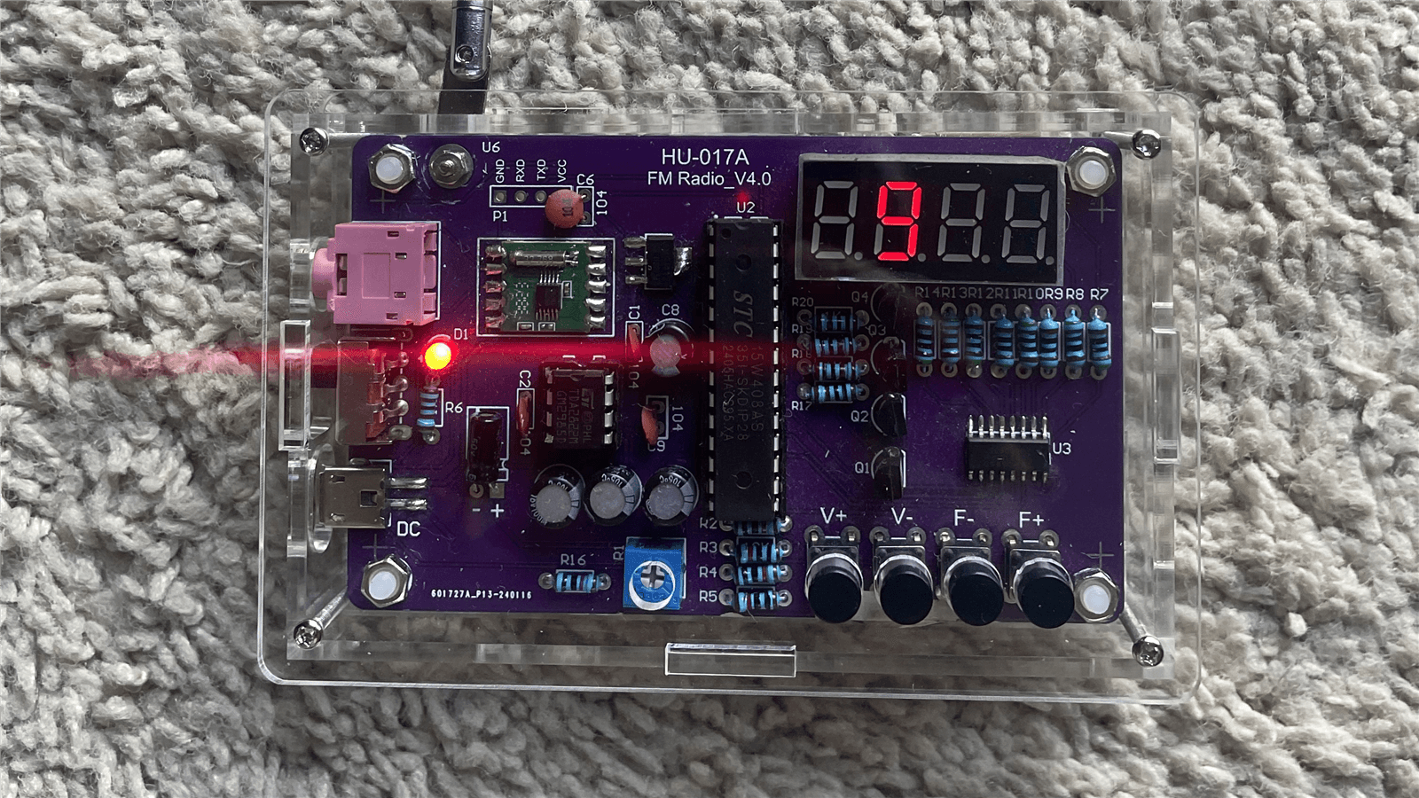 Finished FM/AM radio in a clear acrylic case with a lit seven-segment frequency display and four-button interface
